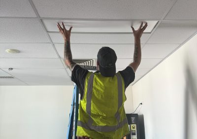 Electrician fitting a ceiling LED panel in a commercial fit-out