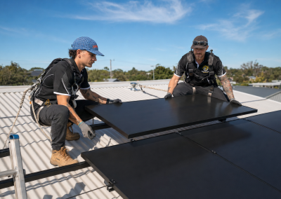 Two installers positioning a solar panel on a roof